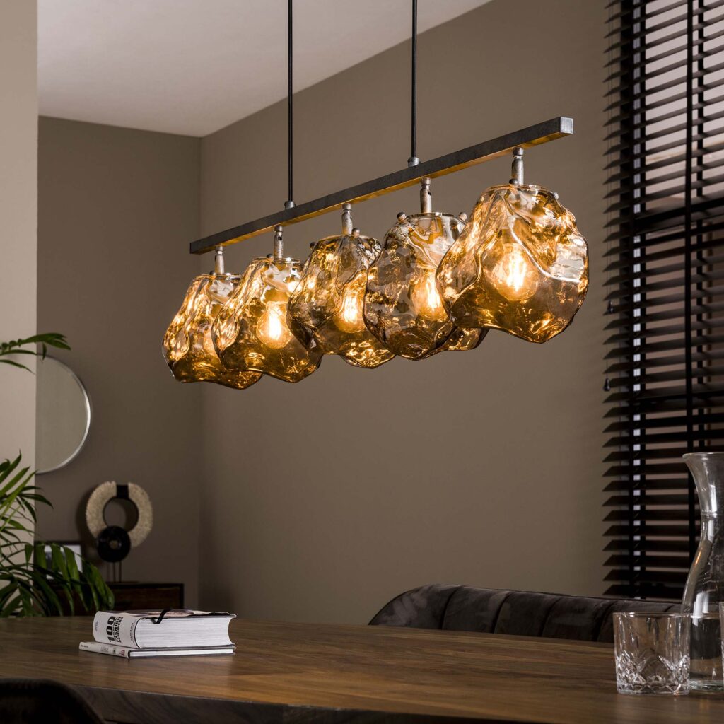 Moderne hanglamp met amberkleurige glazen kappen boven houten eettafel in interieur Belga Meubel Brugge