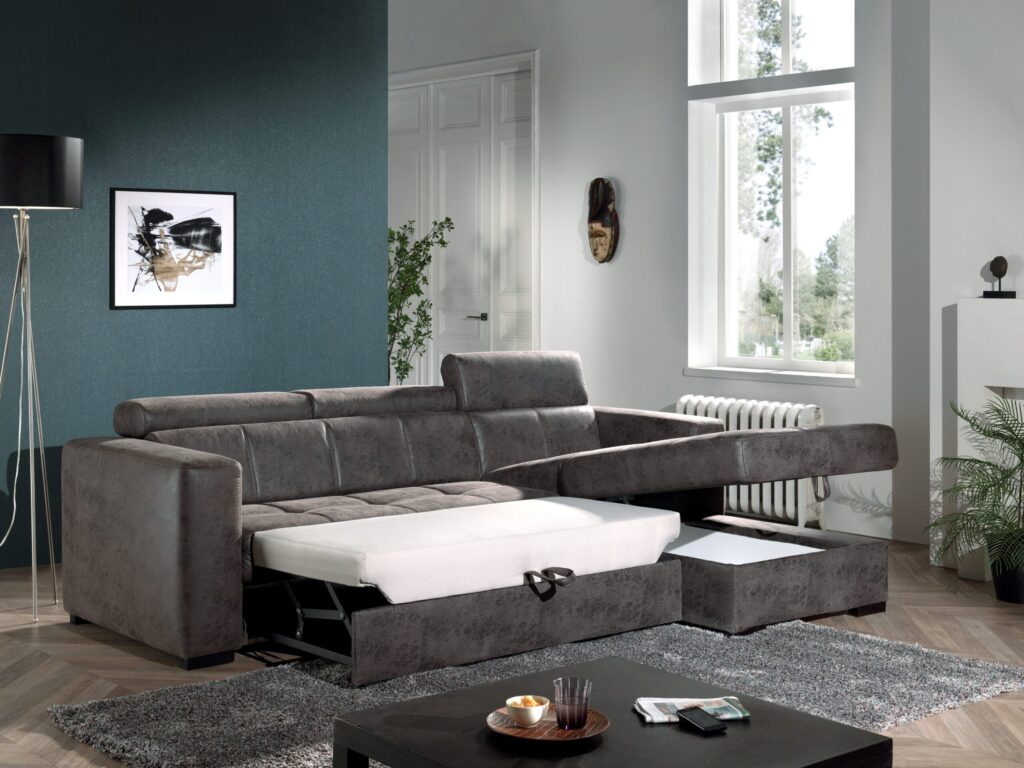 Luxe grijze slaapbank in moderne woonkamer bij Belga Meubel Brugge met grote ramen en stijlvolle inrichting