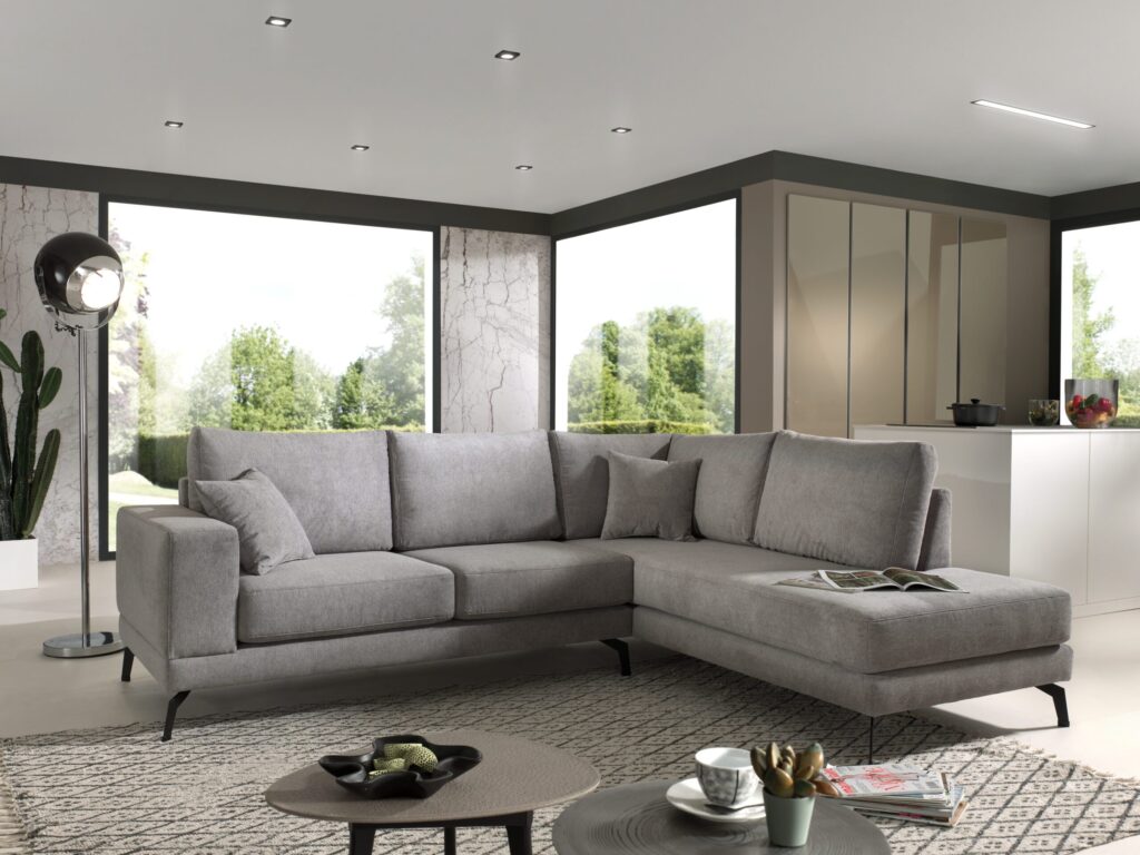 Grijze hoekbank in modern interieur met grote ramen en designlamp bij Belga Meubel Brugge