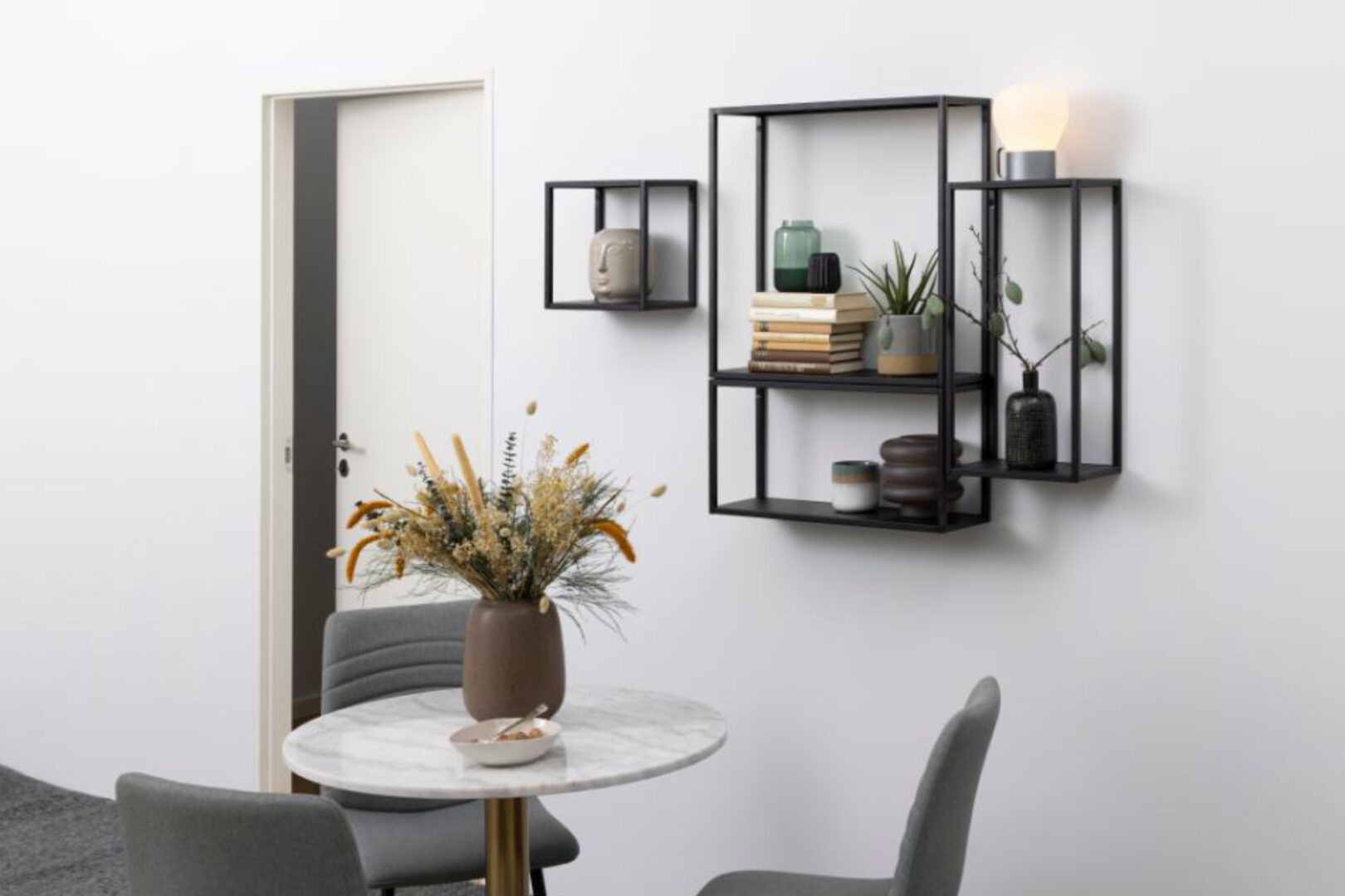 Moderne zwarte wandkasten met decoratie en verlichting, ronde marmeren eettafel met bloemenvaas en grijze stoelen, Belga Meubel Brugge