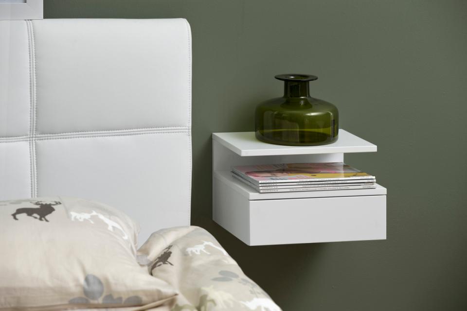 Wit zwevend nachtkastje met lade en tijdschriften, groene glazen vaas, naast wit bed met hoofdbord, Belga Meubel Brugge