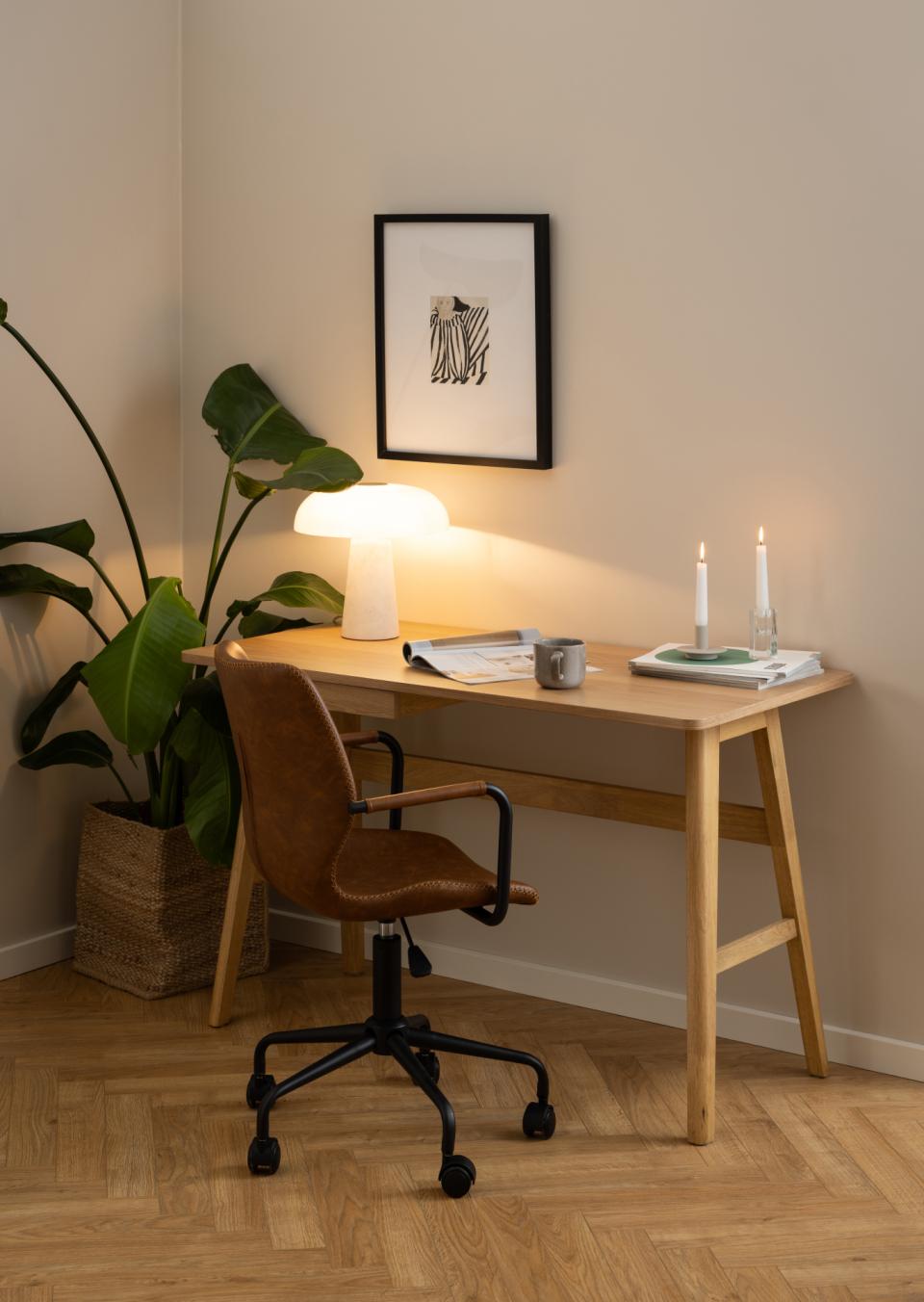 Moderne werkhoek met houten bureau, leren bureaustoel, tafellamp, planten en kaarsen, meubels van Belga Meubel Brugge