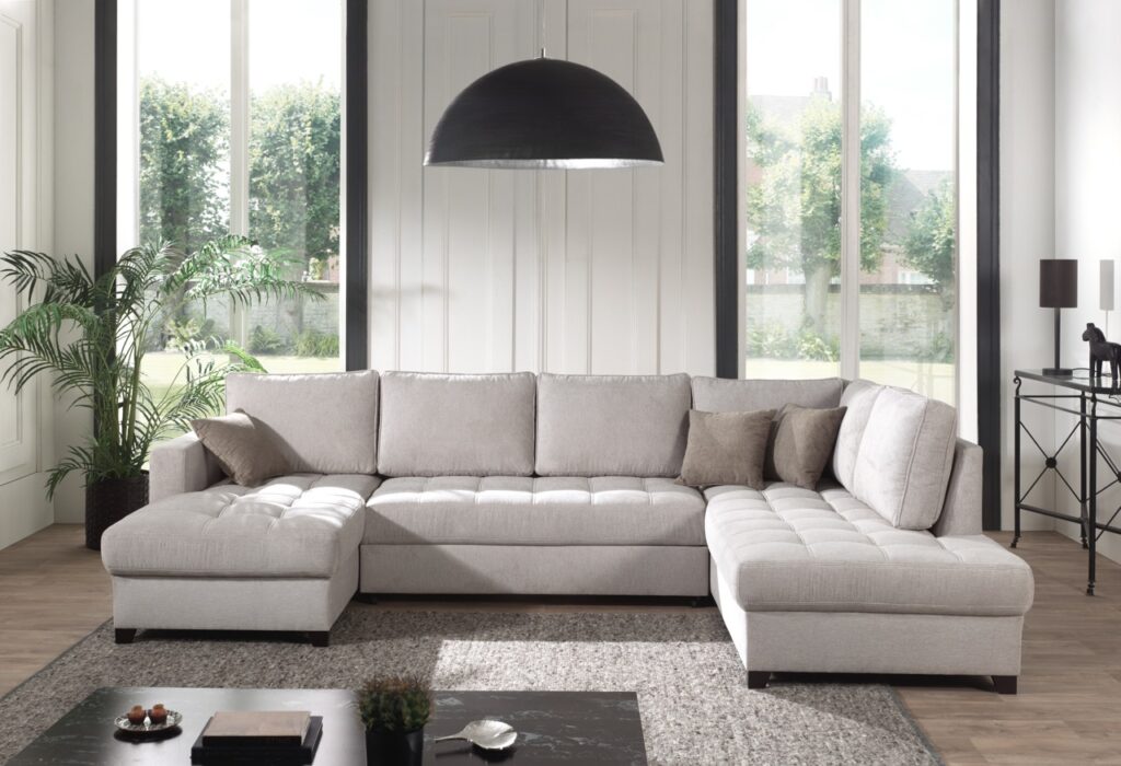 Lichtgrijze hoekbank met kussens in modern woonkamerinterieur bij Belga Meubel Brugge