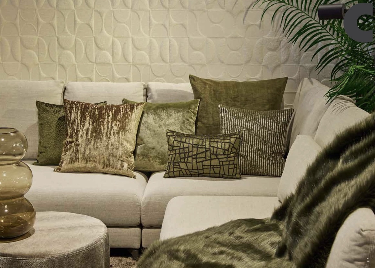 Lichtgekleurde hoekbank met diverse groene kussens en een ronde poef in een gezellige woonkamer