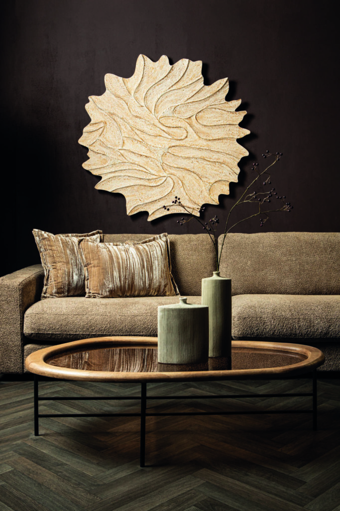 Sfeerfoto woonkamer met beige sofa, sierkussens, houten salontafel en abstracte wanddecoratie bij Belga Meubel Brugge