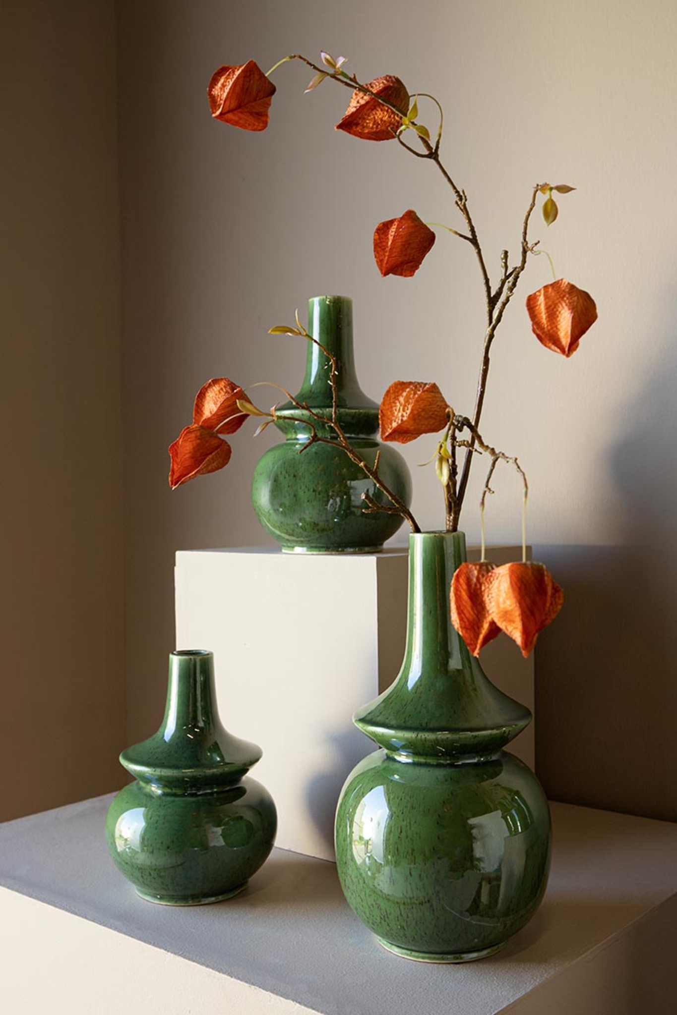 Groene keramische vazen met takken en oranje lampionnetjes decoratie bij Belga Meubel Brugge