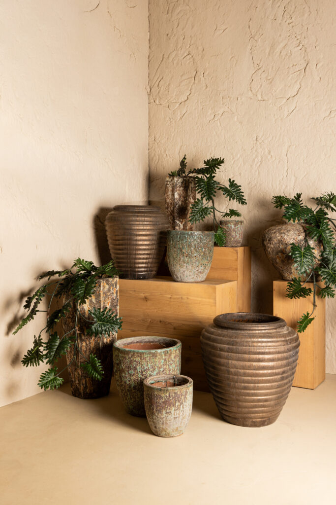 Aardetinten potten met groene planten op houten blokken in een interieur bij Belga Meubel Brugge