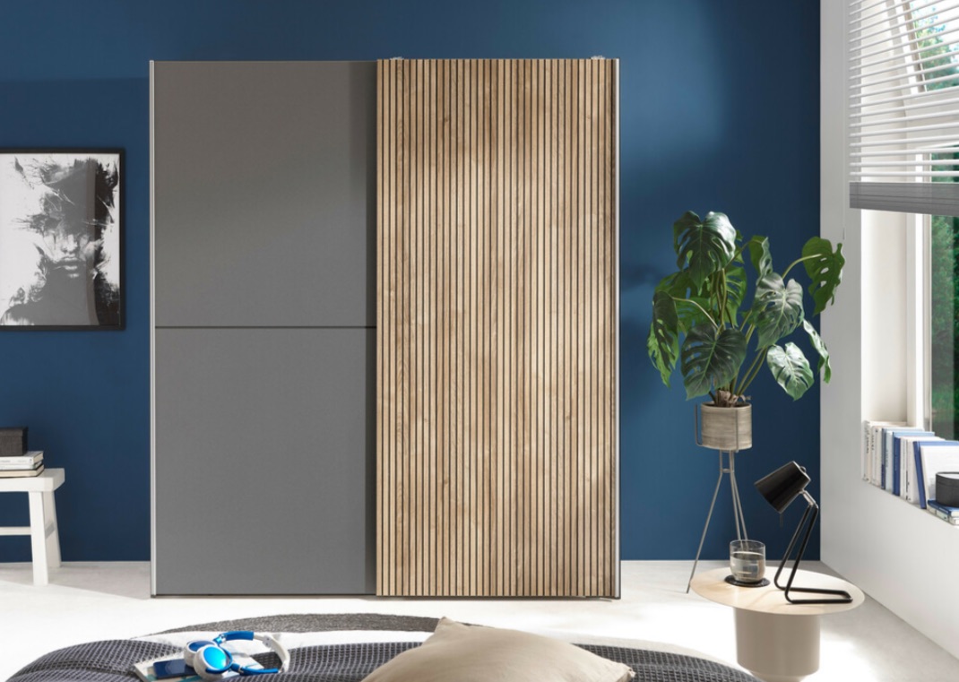 Moderne kast met houten lamellen en grijze deuren in een kamer met blauwe muur en planten