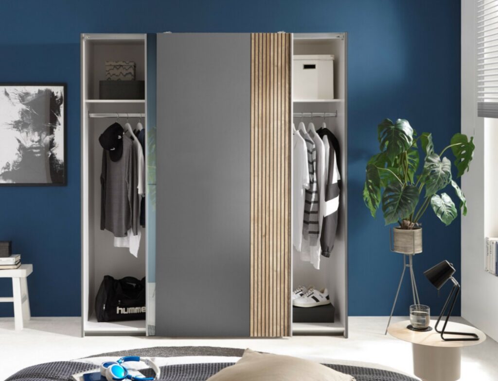 Modern grijze en houten schuifdeurkast met kleding en accessoires in een blauwe slaapkamer