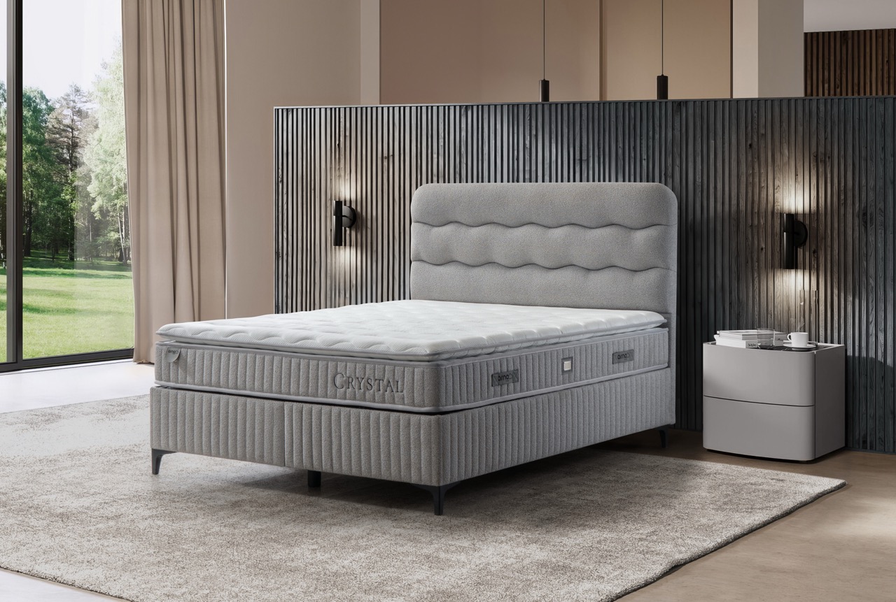 Modern grijs Crystal boxspring bed met golvend hoofdeinde in ruime slaapkamer bij Belga Meubel Brugge