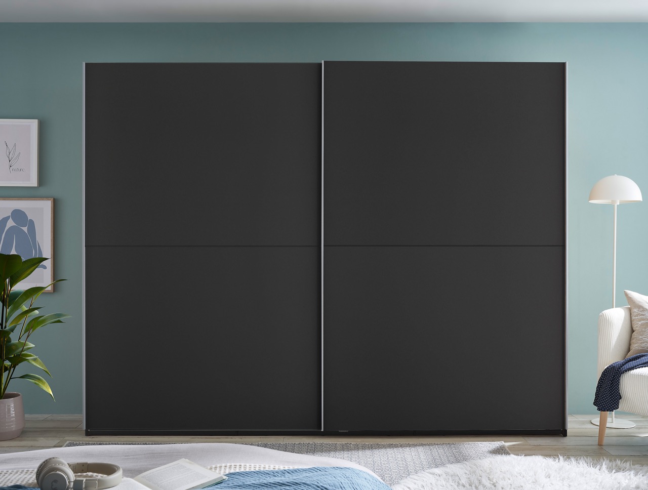 Grote zwarte schuifdeurkast in moderne slaapkamer met blauwgroene muur en minimalistische inrichting